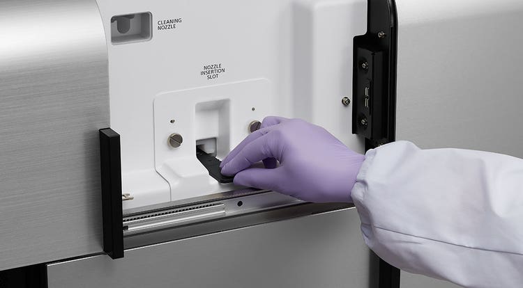 Photo of researcher hand loading a nozzle into the FP7000.