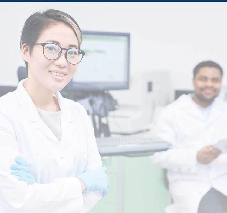 Researcher and colleague smiling in a lab setting.